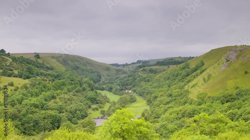 Wide low angle panoramic still shot of lush green countryside Monsal valley landscape with grass and trees against the cloudy sky, Derbyshire, UK photo