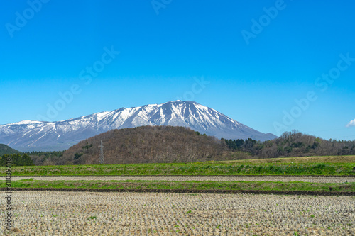Snow capped Mount Iwate with clear blue sky natural background, beauty townscape of Takizawa and Shizukuishi City in springtime season sunny day, Iwate, Tohoku, Japan. Towada-Hachimantai National Park photo
