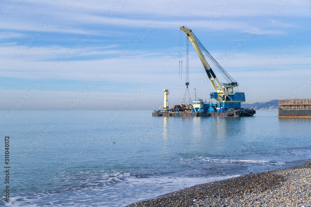 floating crane on a barge near the shore. Construction work in the sea. Construction of engineering structures on the water 