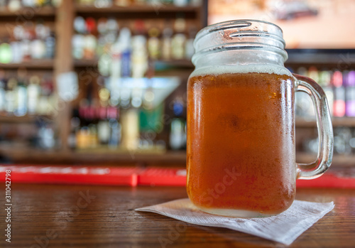 Photo Frosty beer in jar on bar showing condensation.