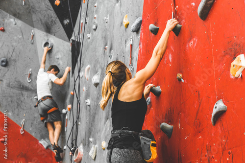 Sportswoman climber moving up on steep rock, climbing on artificial wall indoors. Extreme sports and bouldering concept
