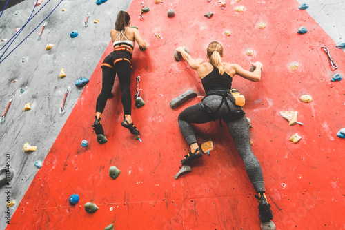 Wspinacz sportowców porusza się po stromej skale, wspinając się na sztucznej ścianie w pomieszczeniu. Sporty ekstremalne i bouldering