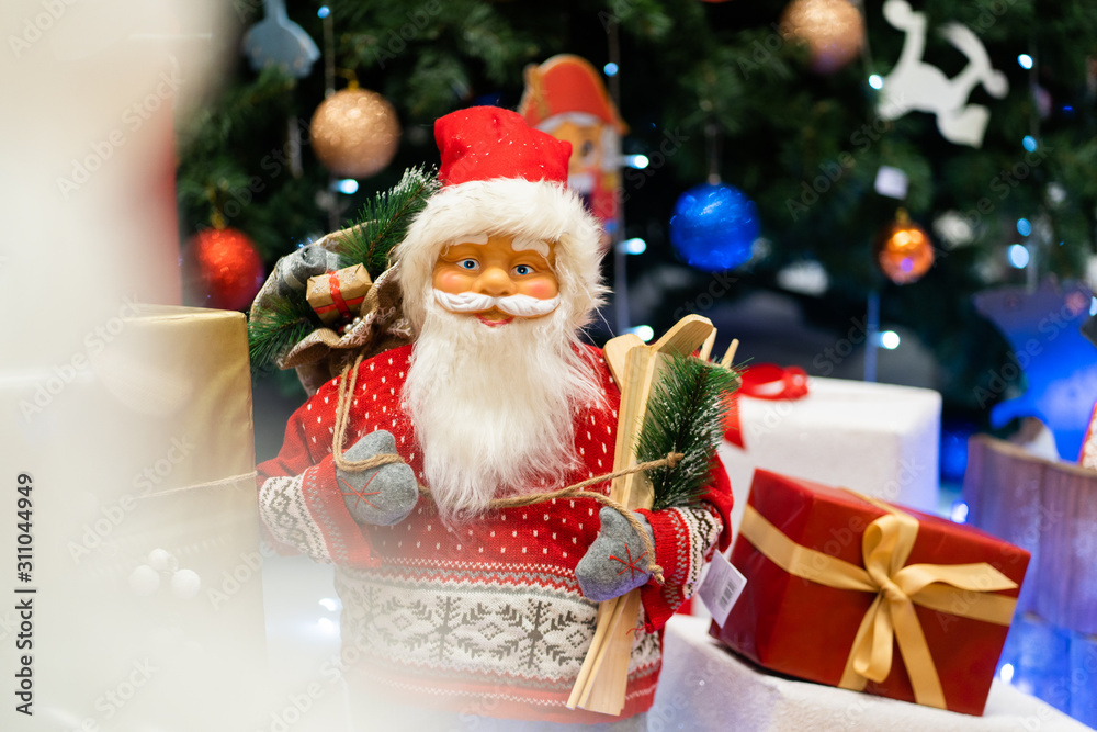 Merry Christmas and Happy new Year , Santa Claus doll with girts in Christmas festival , Copy space. Cute grandfather frost in red costume and gray gloves on tree background. gift and celebration. Merry Christmas and Happy new Year , Santa Claus doll with girts in Christmas festival , Copy space. Cute grandfather frost in red costume and gray gloves on tree background. gift and celebration.