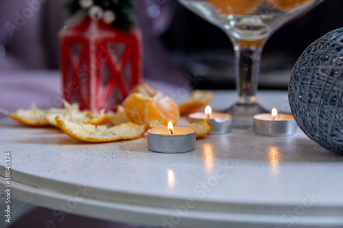 Christmas candles and tangerines on the table against the background of New Year's decor. Christmas association.