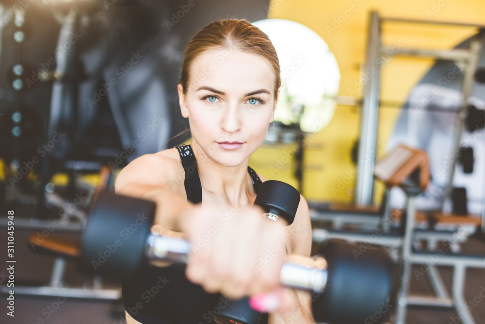 Working out with dumbbell weights at the gym.Fitness Women exercising are lifting dumbbells. Fitness muscular body.Workout at gym. Working out with dumbbell weights at the gym.Fitness Women exercising are lifting dumbbells. Fitness muscular body.Workout at gym.