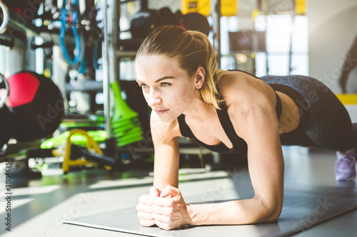 Woman in the gym is warming up before training, stands in plank