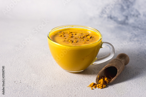 Golden turmeric milk on the white background with spices cinnamon and ingredients