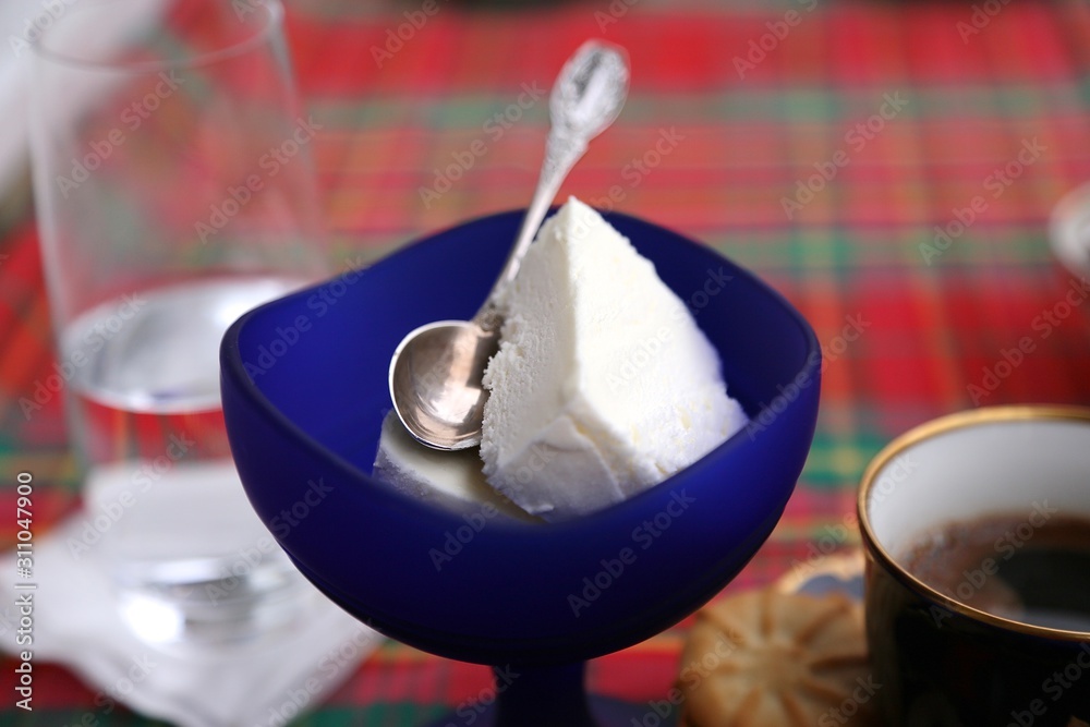 A teaspoon in a blue ice cream cup on the table, a glass of water and a cup of coffee A teaspoon in a blue ice cream cup on the table, a glass of water and a cup of coffee