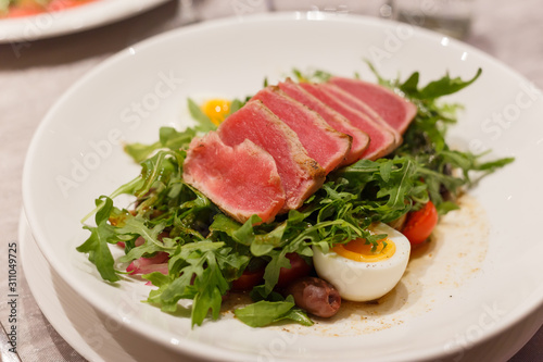 Meat carpaccio with arugula olives and soft-boiled egg. Serving in a restaurant