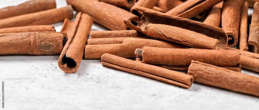 Heap of cinnamon bark sticks on white stone like board - space for text left down corner Heap of cinnamon bark sticks on white stone like board - space for text left down corner