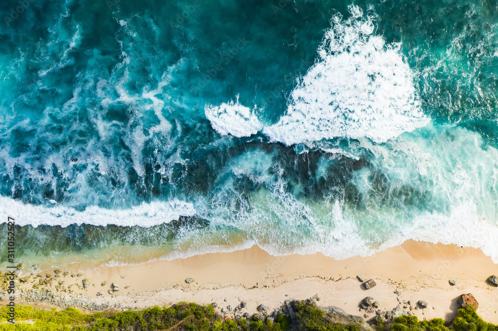 View from above, stunning aerial view of a rocky shore with a beautiful beach bathed by a rough sea during sunset, Nyang Nyang Beach (Pantai Nyang Nyang), South Bali, Indonesia.