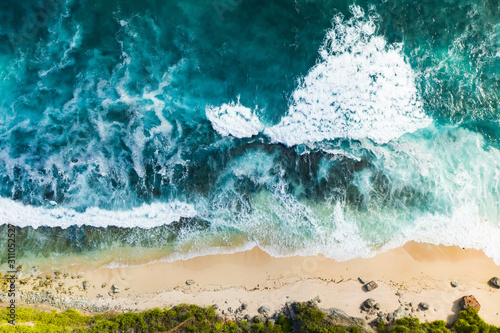 View from above, stunning aerial view of a rocky shore with a beautiful beach bathed by a rough sea during sunset, Nyang Nyang Beach (Pantai Nyang Nyang), South Bali, Indonesia.