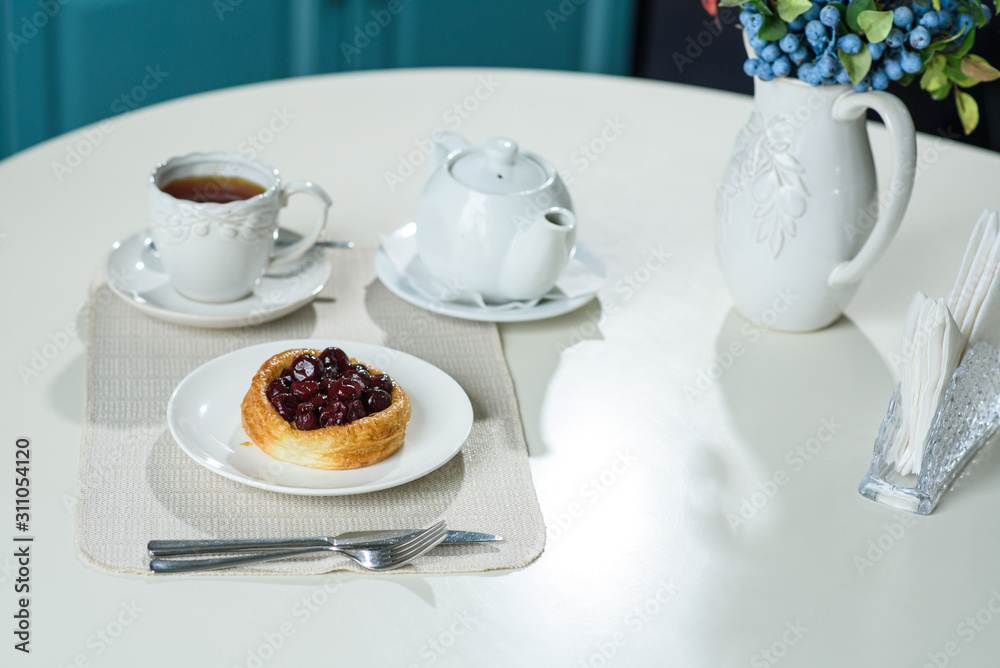 Danish with cherries and black tea on a table in a cozy coffee shop