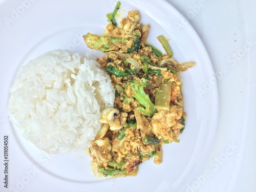 Stir fry mixed-seafood with with yellow curry powderin thai style with fried egg and rice in in white plate on white background. photo