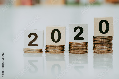 Wooden word number 2020 on stack of coins and blurred city scape with copy space for text using as background business investment, new year, real estate, property concept.