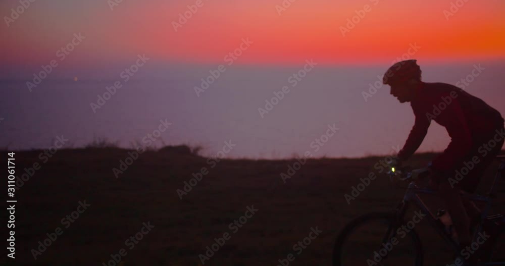 man cycling on a cliff in beautiful colorful dusk man cycling on a cliff in beautiful colorful dusk