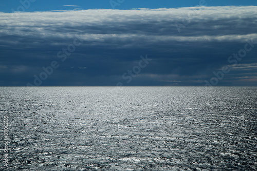 The Picture from a ferry between Sweden and Finland. The contrast between the dark cloudy sky and bright water with sun reflection.
