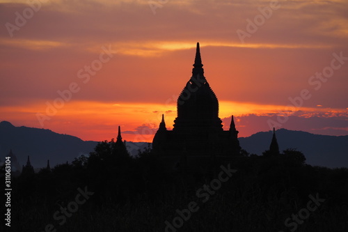 Beautiful silhouette focus of the old pagodas and Buddhist temples in Bagan Myanmar during sunset time with dark colorful and warm sky and mountain background. Religious landmark for tourism in Asia