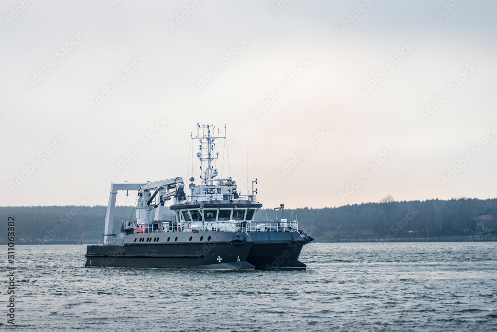 A small commercial vessel sails near the island into the sea in cloudy weather. A small commercial vessel sails near the island into the sea in cloudy weather.