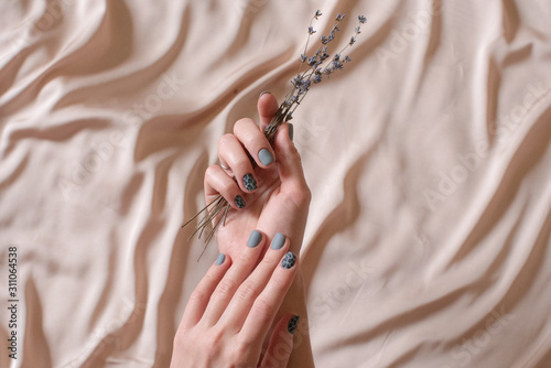 Beauty concept. Hand skin care. Closeup of beautiful woman hands with light manicure on nails. flowers in the hand photo