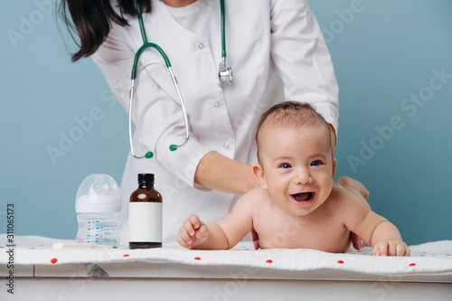 little baby boy lies on a table on his stomach at a doctor's appointment