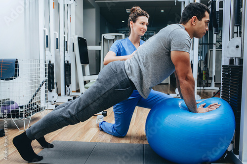 Fototapeta Naklejka Na Ścianę i Meble -  physiotherapist helps a man doing exercises for the rehabilitation and restoration of the body. Center for the treatment of military after injuries