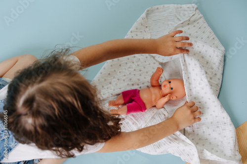 A Girl plays with baby doll on the floor