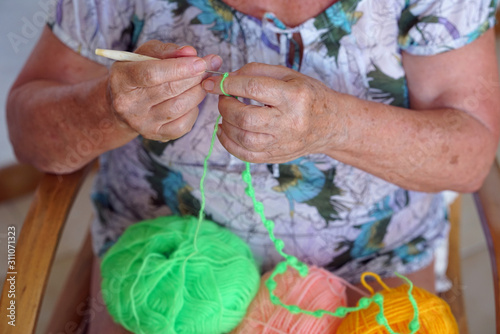 Detail of the hands of an elderly woman doing knitting