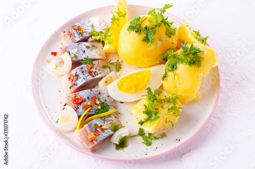 pieces of salted herring in spices with boiled potatoes