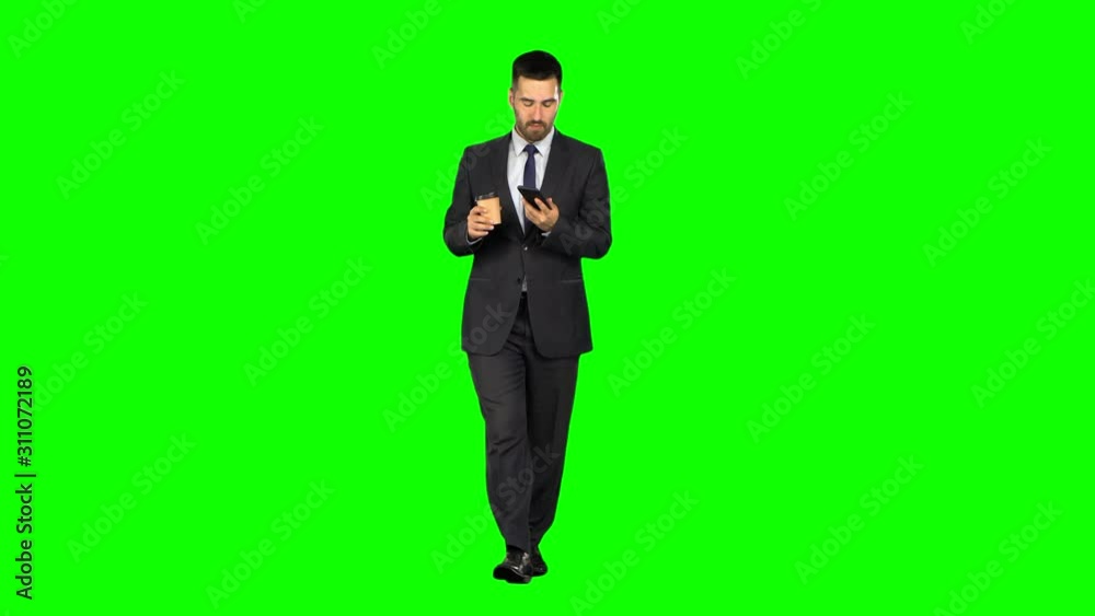 Happy young Businessman reads news messages on a mobile phone and drinks coffee on green background, Chroma key Happy young Businessman reads news messages on a mobile phone and drinks coffee on green background, Chroma key