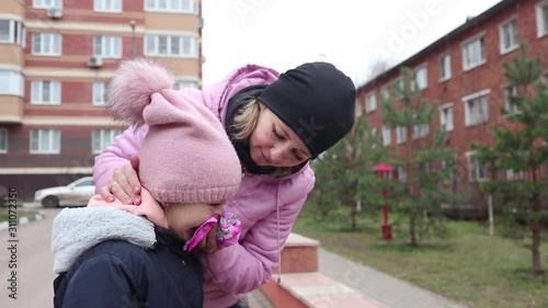 mother blows her daughter's nose with a handkerchief in autumn when it's cold