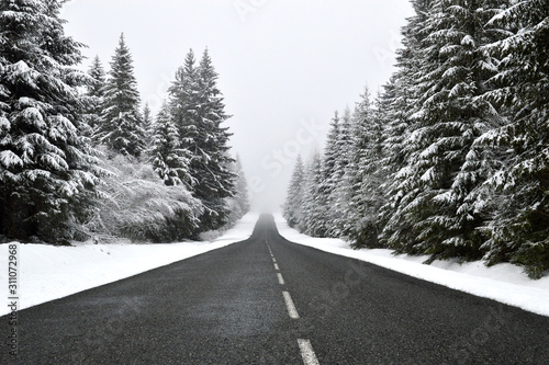 A dangerous slippery mountain road during the winter with low visibility.