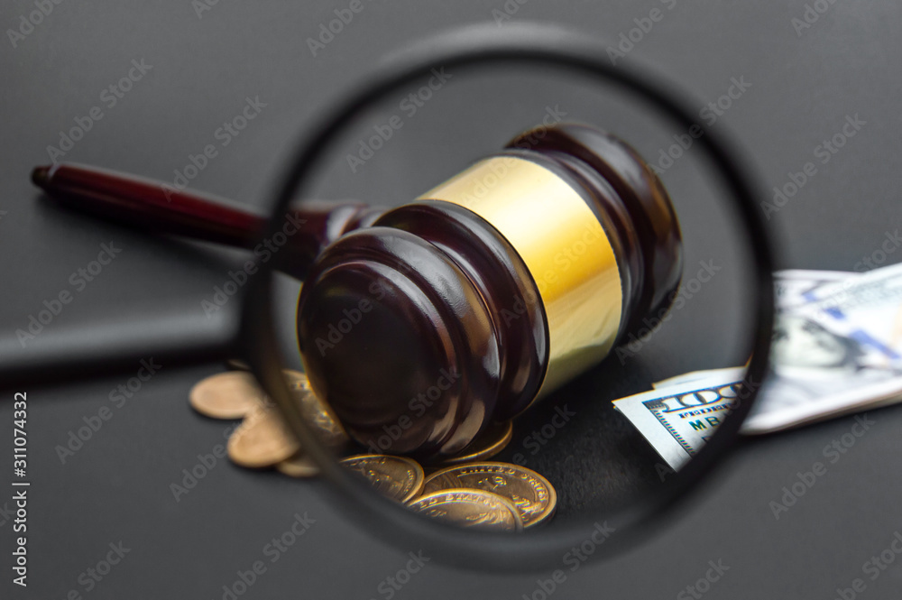 Magnifying glass with view of judge's gavel and money.