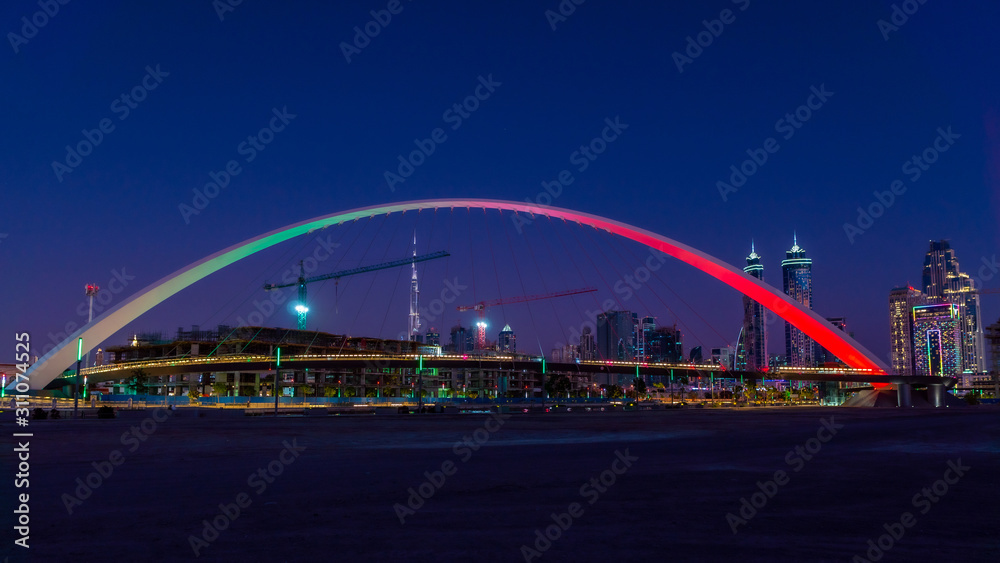 Obraz premium Panoramic night view on Dubai at blue hour, showing Bridge of tolerance and iconic buildings and construction cranes