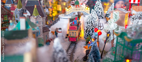 Christmas village. Houses, railway and train, outdoor activities, sleighs, ice skates in a snowy Christmas landscape at night. Christmas tree and snowman. concept for greeting card or postcard Banner