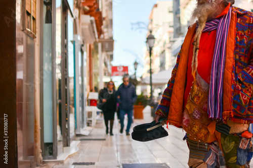 Old Man in Colorful Clothes asking for Alms on the street during Christmas Period