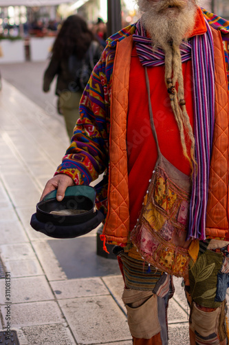 Old Man in Colorful Clothes asking for Alms on the street during Christmas Period