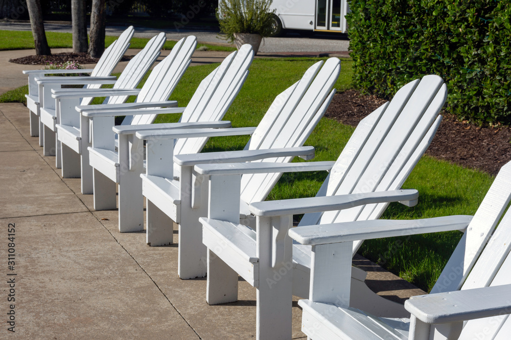 A row of crisp white Adirondack chairs suggests luxury travel or a private country club.