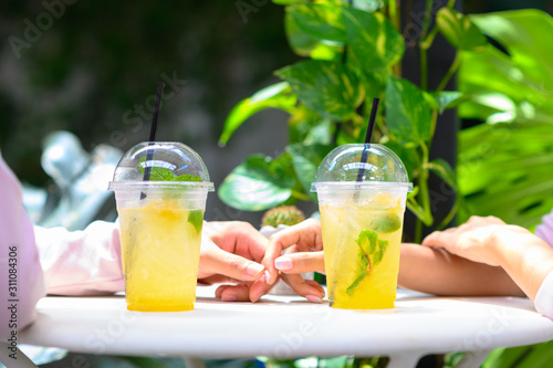 Cropped image of young couple in love drinking soft-drink in cafe