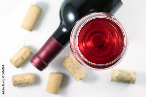 Glass, bottle of red wine, cork from bottles on a white background