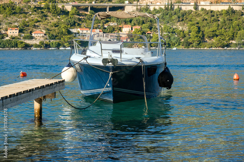 Speedboat with moored buoys tied up to a wooden pier