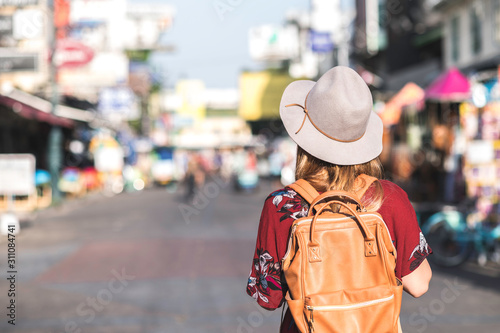 Travel Thailand concept. Young woman with hat traveling in walking street Khaosan road in Bangkok, Thailand