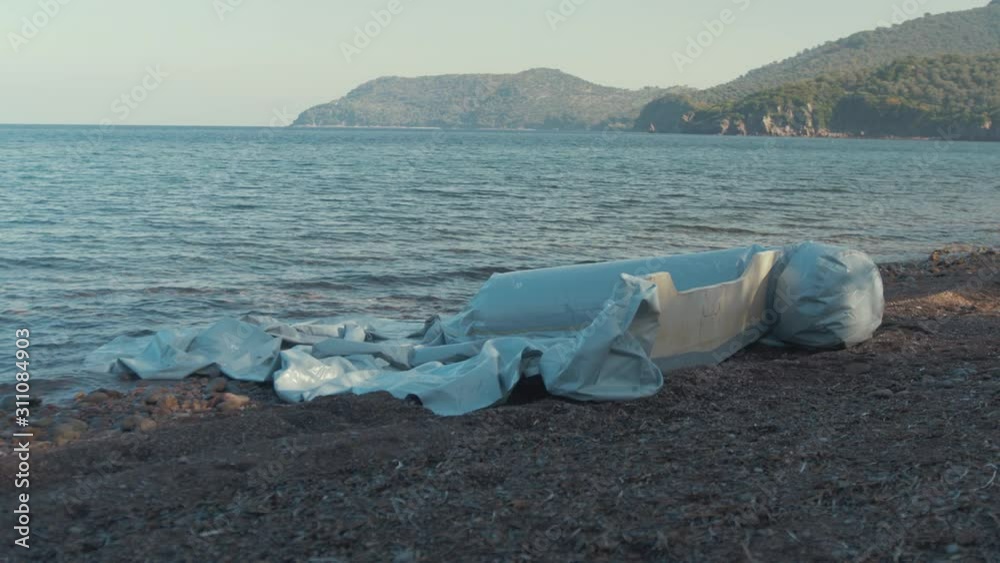 Refugee dinghy deflated on Greek shoreline Refugee dinghy deflated on Greek shoreline