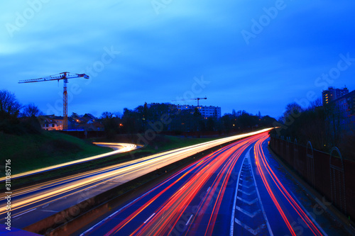 Lightpainting of a highway at night with road traffic. Spun from car headlights in long exposure mode. City in the background. 