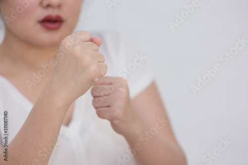 A picture of a woman raising a fist in her hand to show resistance and wanting to stop the violence in Concept Violence against women in a white background.