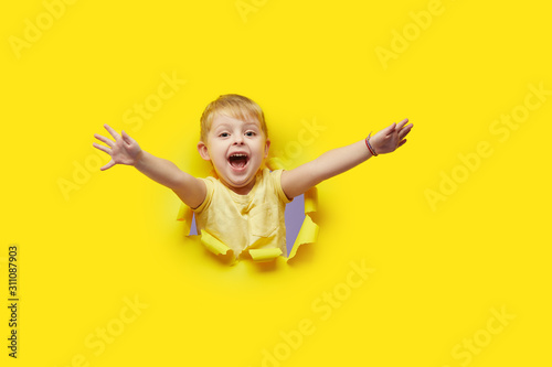 Φωτογραφία Little child looking, peeping through the bright yellow paper hole