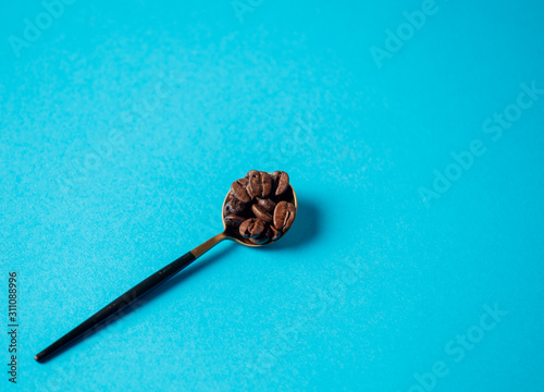 teaspoon with coffee grains on a blue background