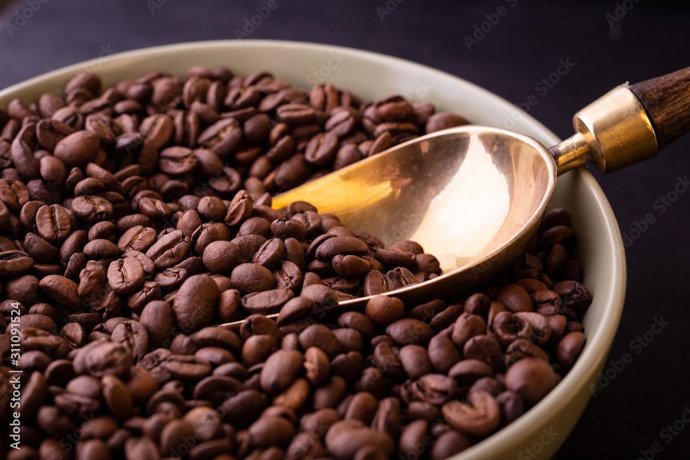 Fototapeta premium Coffee theme. Plate with coffee beans on black wooden table.
