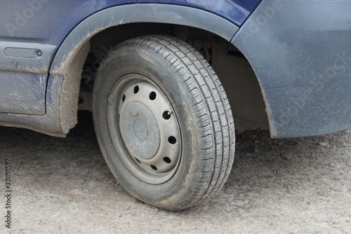 one gray dirty wheel on a blue car in the street © butus