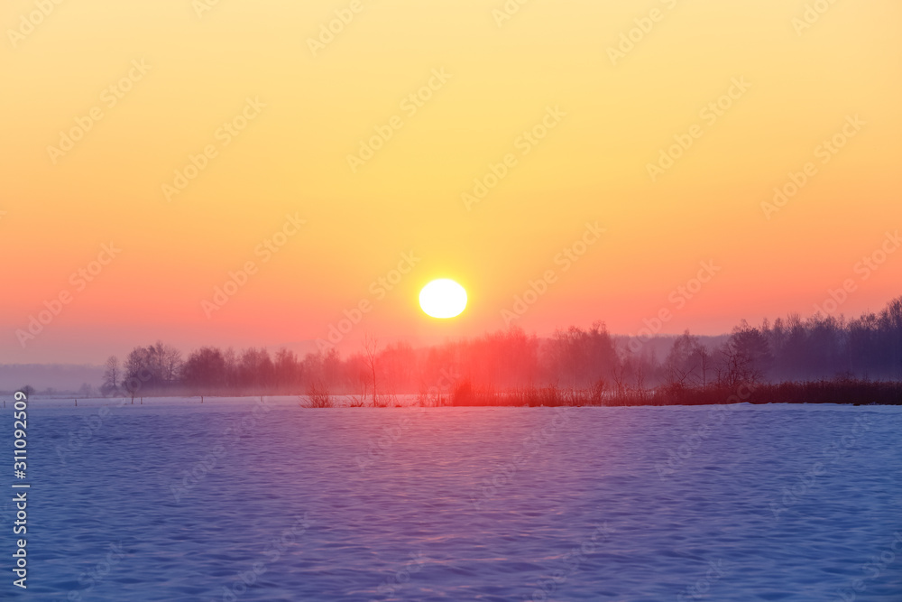 Fantastic winter morning. Landscape with fields, mountain, forest and meadow covered with snow. Beautiful sunrise, cloudy sky and orange colorful horizon. Picturesque resort. Rural scenery.